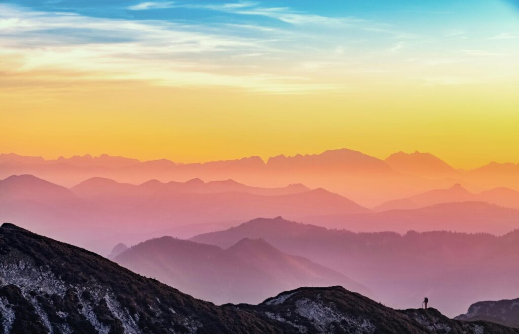 Dreamlike mountain landscape with cascading ridges and a warm, luminous dawn gradient.