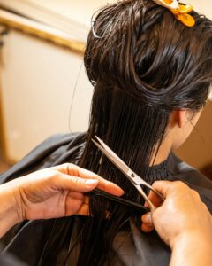 Stylist cutting hair with scissors, back view