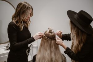 Stylist working on a client's hair extensions in the salon