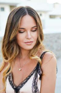 Woman with soft balayage waves and a delicate necklace